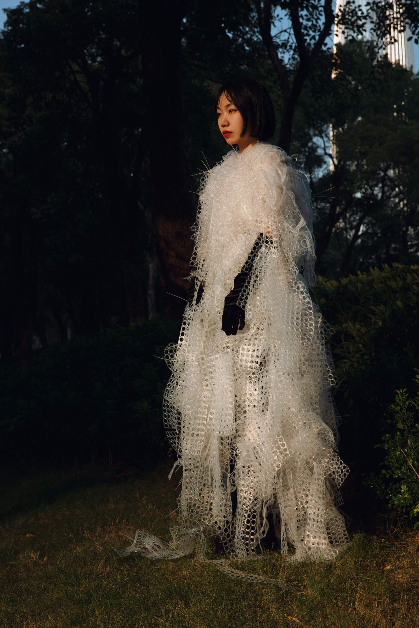 Yuling Yu wearing a white sculptural material work outdoors