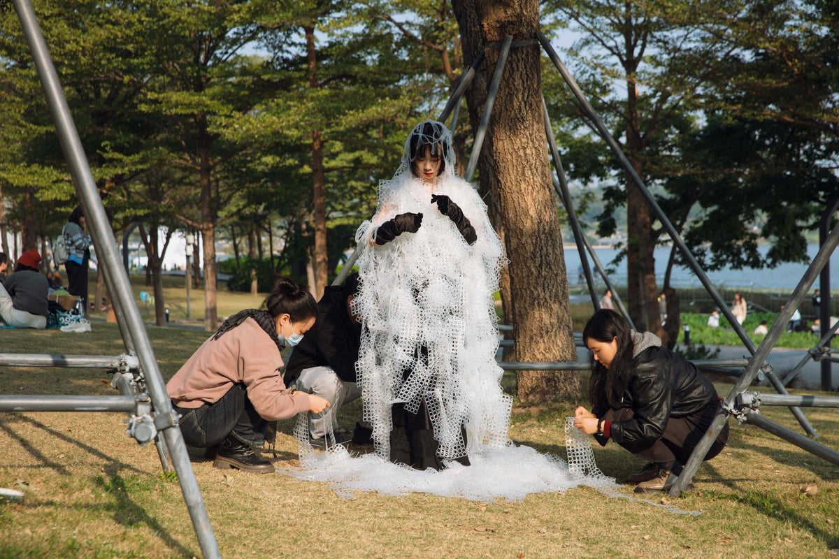 Participants sewing rubber netting onto the body during a performance artwork